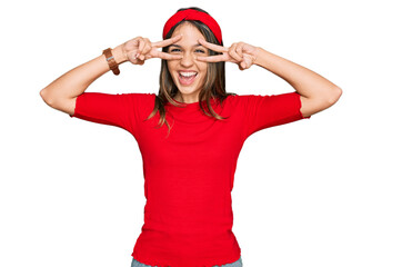 Obraz na płótnie Canvas Young brunette woman wearing casual clothes doing peace symbol with fingers over face, smiling cheerful showing victory