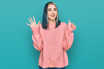 Young modern girl wearing pink wool winter sweater showing and pointing up with fingers number six while smiling confident and happy.