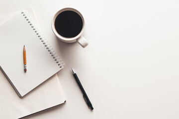 Office desk table with supplies, coffee cup and flower. Top view