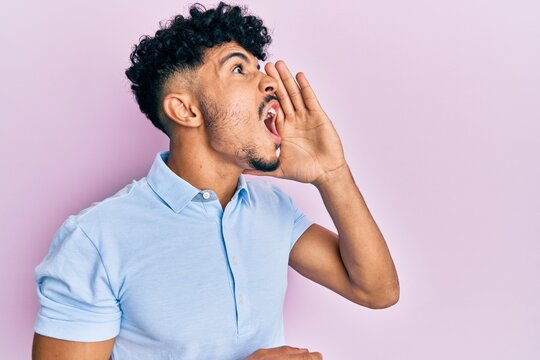 Young arab handsome man wearing casual clothes shouting and screaming loud to side with hand on mouth. communication concept.