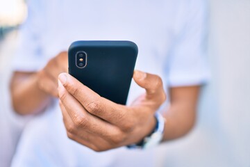 Young arab man smiling happy using smartphone leaning on the wall.