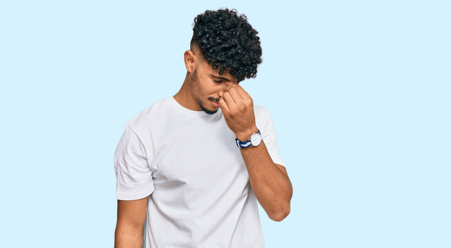 Young arab man wearing casual white t shirt tired rubbing nose and eyes feeling fatigue and headache. stress and frustration concept.