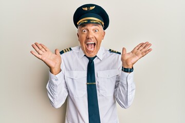 Handsome middle age mature man wearing airplane pilot uniform celebrating crazy and amazed for success with arms raised and open eyes screaming excited. winner concept