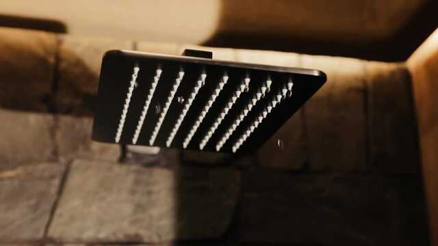 Falling water drops frop shower head. Shower head in bathroom dripping, waste of water.