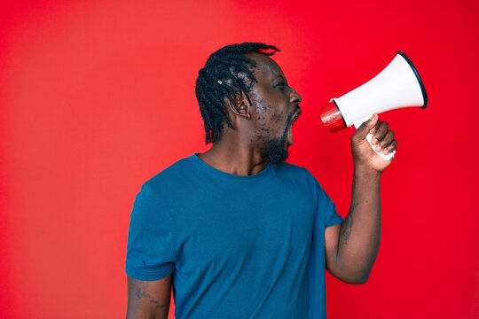 Young handsome african american man screaming using megaphone over isolated red background