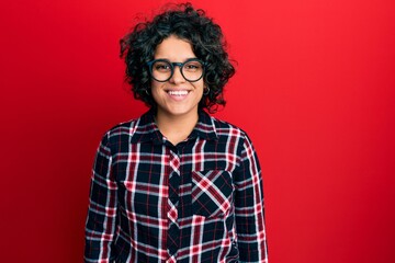Young hispanic woman with curly hair wearing casual clothes and glasses with a happy and cool smile on face. lucky person.
