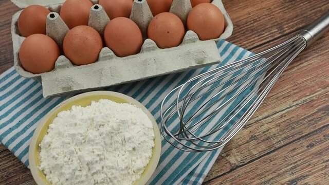 bo&icirc;te d'oeufs, farine et fouet de cuisine sur une table