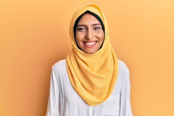 Young brunette arab woman wearing traditional islamic hijab scarf with a happy and cool smile on...