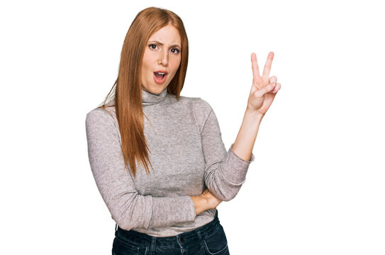 Young irish woman wearing casual clothes smiling with happy face winking at the camera doing victory sign. number two.