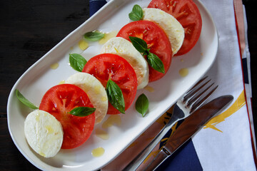 Caprese salad with ripe tomatoes and mozzarella cheese, with fresh basil leaves and olive oil

