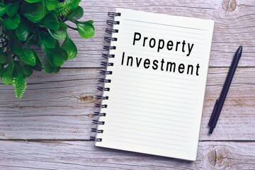 Text on notebook with pen and plant on wooden desk - Property investment