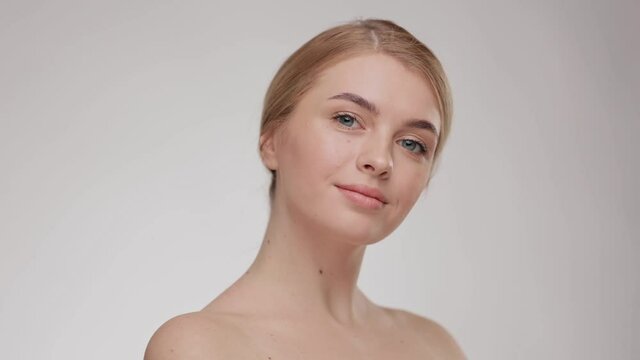 Close up portrait young beautiful blonde girl. Adorable young half-naked woman look at the camera and smiling. Beauty and skin care. Advertising fresh clean healthy skin care concept.