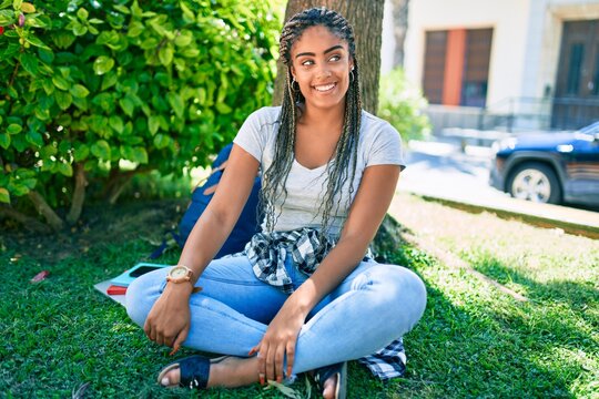 Young african american student woman smiling happy sitting on the grass at the university campus