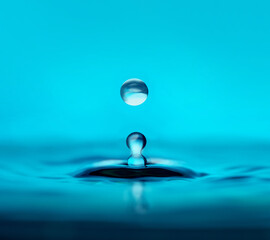 Fototapeta na wymiar Water drop falling into water making a perfect droplet splash