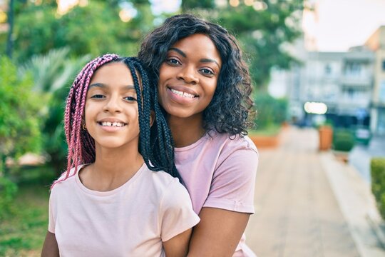 Beautiful african american mother and daughter smiling happy and hugging. Standing with smile on face standing at the park.