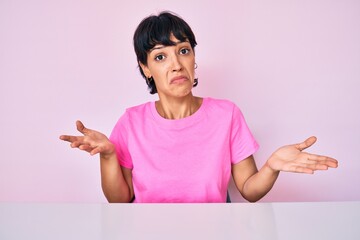 Beautiful brunettte woman wearing casual clothes over pink background clueless and confused...