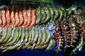 Bunch of fresh uncooked shrimps on display among ice for sale at a local market stall