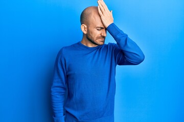 Young hispanic man wearing casual winter sweater surprised with hand on head for mistake, remember...