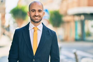 Fototapeta premium Young hispanic bald businessman smiling happy standing at the city.