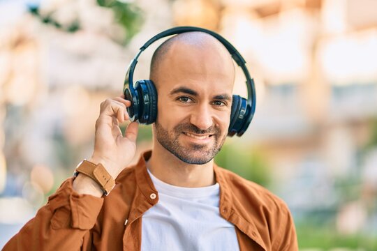 Young hispanic bald man smiling happy using headphones at the city
