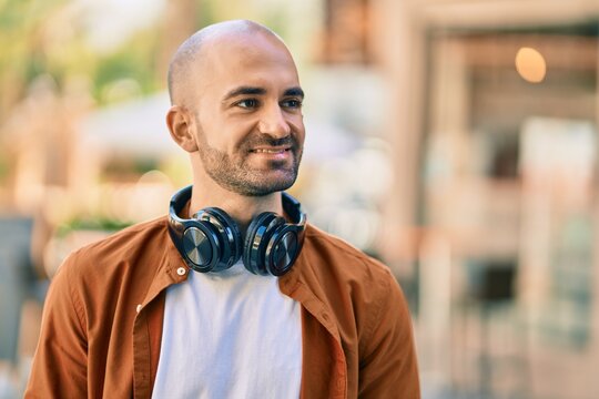 Young hispanic bald man smiling happy using headphones at the city