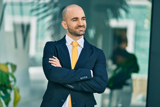 Young hispanic bald businessman with arms crossed smiling happy at the city.