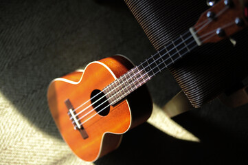 Fototapeta na wymiar High angle view wooden brown ukulele lay on the sofa at home