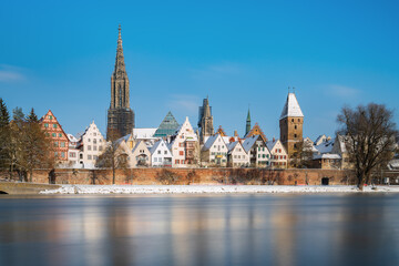 City Ulm with river danube in winter at sunrise with blue sky and snow. Ulmer minster and tower metzgerturm. Panorama long exposure. Travel, vacation - obrazy, fototapety, plakaty