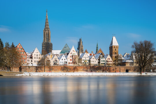 City Ulm with river danube in winter at sunrise with blue sky and snow. Ulmer minster and tower metzgerturm. Panorama long exposure. Travel, vacation