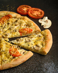 pizza close-up with cheese and tomatoes on a dark background with ingredients