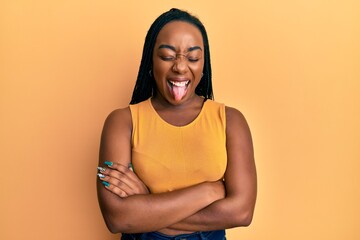 Young african american woman with arms crossed gesture sticking tongue out happy with funny expression.