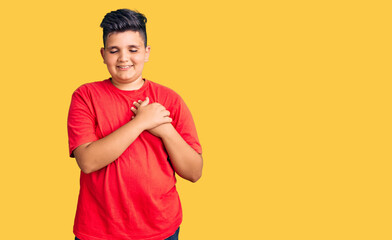 Little boy kid wearing casual clothes smiling with hands on chest with closed eyes and grateful...