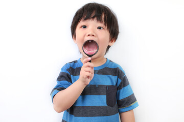 Portrait of Asian boy using a magnifying glass. Cute little boy showing his mouth using a magnifying glass.