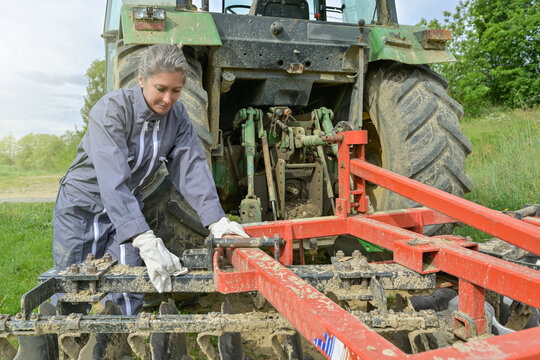 Female farmer adjusting the plow behing the tractor