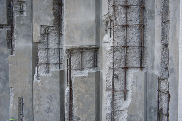 Damaged concrete walls with exposed steel reinforcements inside.
