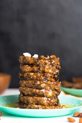 homemade oatmeal banana pancakes with chia seeds, almonds, prunes and dates, drizzled with honey and crushed nuts on a dark background. diet breakfast is healthy for the figure .