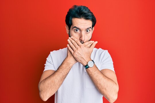 Young hispanic man wearing casual white tshirt shocked covering mouth with hands for mistake. secret concept.