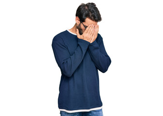 Young hispanic man wearing casual clothes and glasses with sad expression covering face with hands while crying. depression concept.