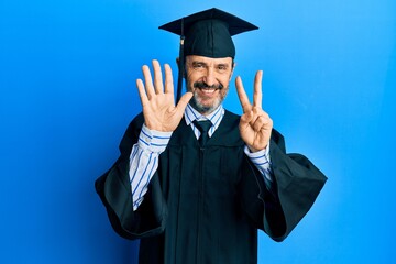 Middle age hispanic man wearing graduation cap and ceremony robe showing and pointing up with fingers number seven while smiling confident and happy.