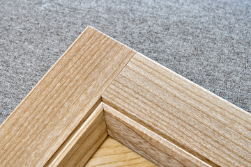 Stylish new detail of furniture facade made of light veneer and solid textured ash wood on gray textile background close view