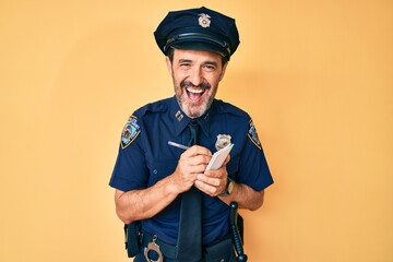 Middle age hispanic man wearing police uniform writing traffic fine smiling and laughing hard out loud because funny crazy joke.