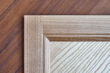 Stylish new detail of furniture facade made of light veneer and solid textured ash wood on brown wooden desk close view