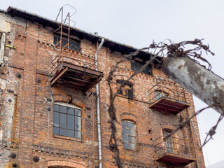 Old brick building fenced by a wall with a mesh.