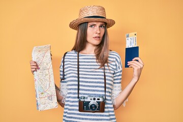 Beautiful caucasian tourist woman holding city map and passport clueless and confused expression. doubt concept.
