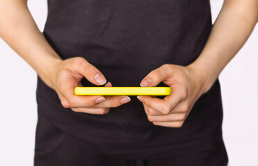 The girl holds a mobile phone in her hands and plays online games at home over WI-FI close-up. Teenagers with a mobile phone. Women's hands typing a text message on a smartphone, online communication