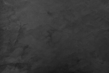 Black textured background made of rough aged plaster with space for text