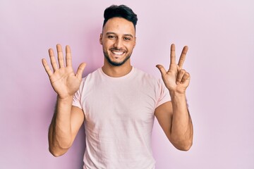 Young arab man wearing casual clothes showing and pointing up with fingers number eight while smiling confident and happy.