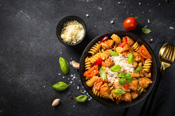 Pasta chicken with vegetables. Served with parmesan. Top view at black table.