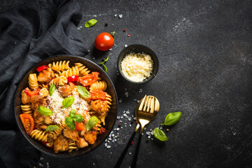 Pasta chicken with vegetables. Served with parmesan. Top view at black table.