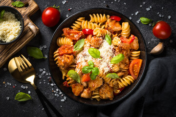 Pasta chicken with vegetables. Served with parmesan. Top view at black table.